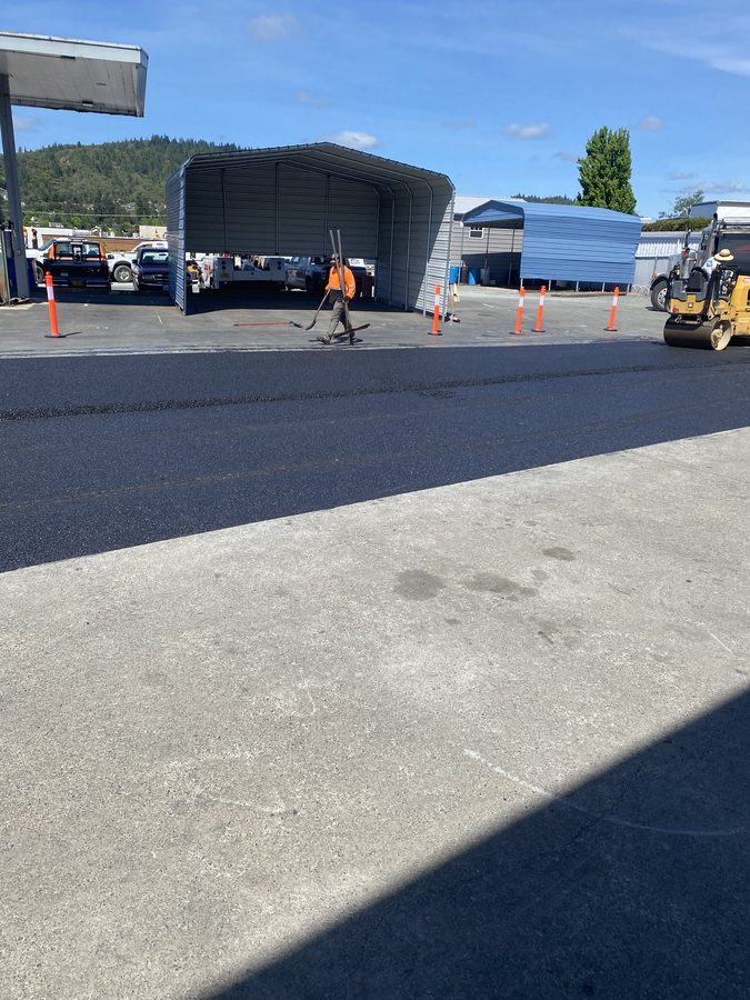 New hot-mix asphalt being compacted with a roller on the Caveman Towing commercial lot in Grants Pass, Oregon