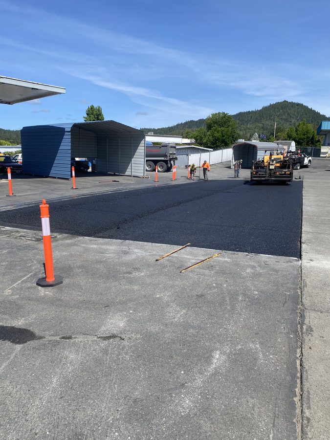 Fresh hot-mix asphalt paved alongside a concrete apron at Caveman Towing in Grants Pass, Oregon