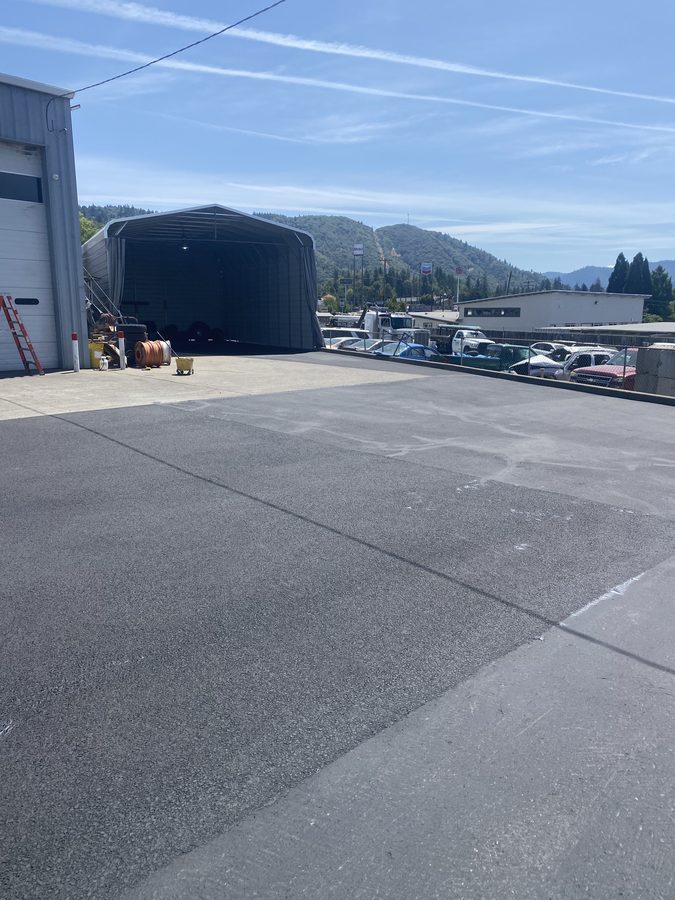 Sealcoated asphalt around the covered work bays at Caveman Towing in Grants Pass, Oregon