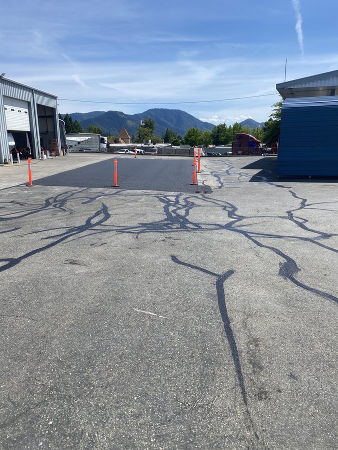 Freshly applied rubberized crack filler across the Caveman Towing lot in Grants Pass, Oregon