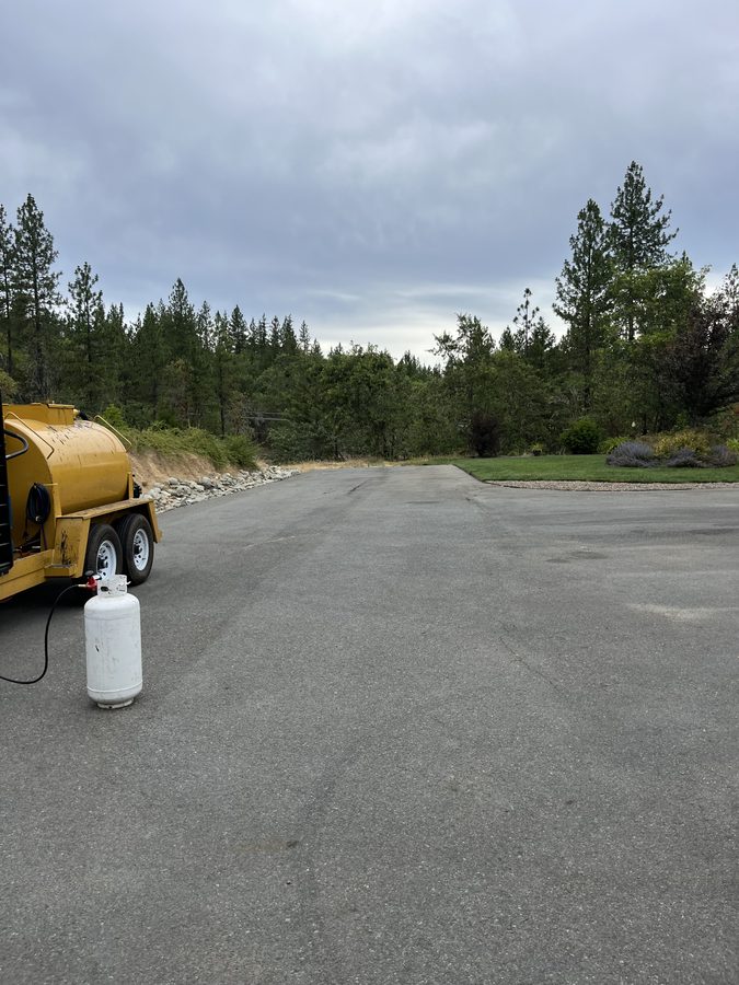 Hot-pour crack-filling kettle and sealer parked on a residential asphalt driveway on Seclusion Loop in Grants Pass, Oregon