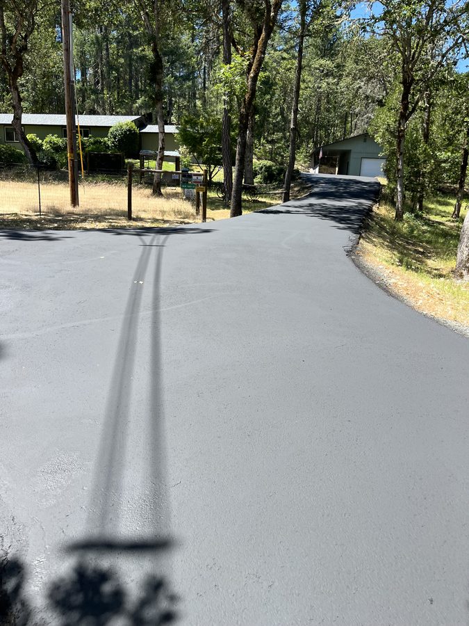 Long private asphalt driveway freshly sealcoated to a smooth, even finish on Lower River Road in Grants Pass, Oregon