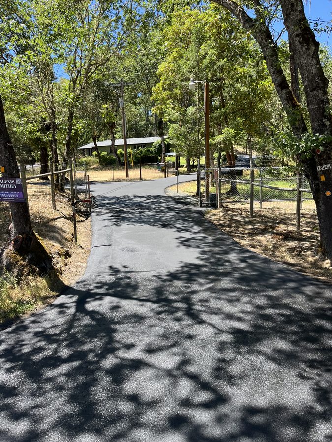 Freshly sealcoated driveway section blocked off with caution tape while the sealer cures on Lower River Road in Grants Pass, Oregon