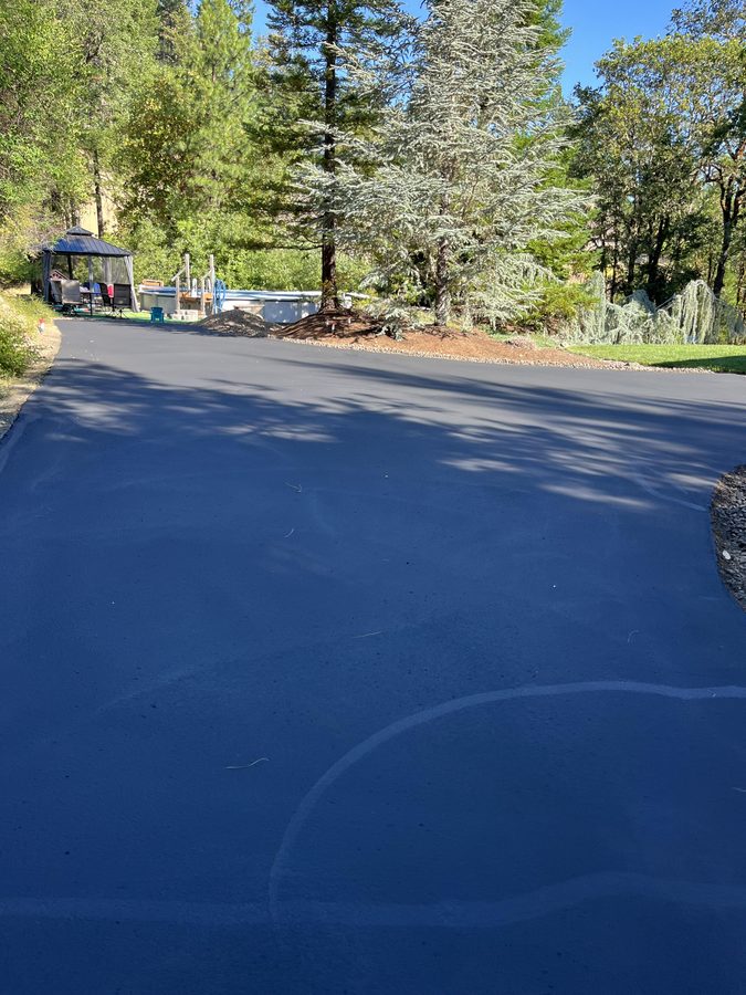 Wide asphalt driveway turnaround sealcoated to a deep black finish beside a gazebo and pool on Seclusion Loop in Grants Pass, Oregon